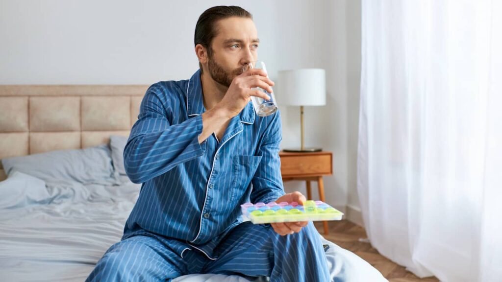 homme sur son lit prend des pilules