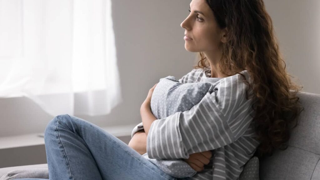 Solitude émotionnelle : pourquoi peut-on se sentir seul même entouré ? femme seule coussin